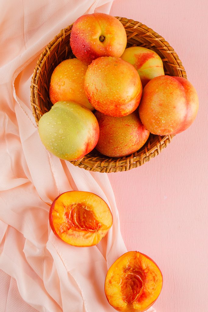Nectarines basket top view pink textile surface 683x1024