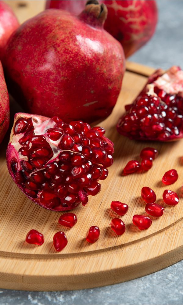 Sliced ripe pomegranate wooden board 600x1000