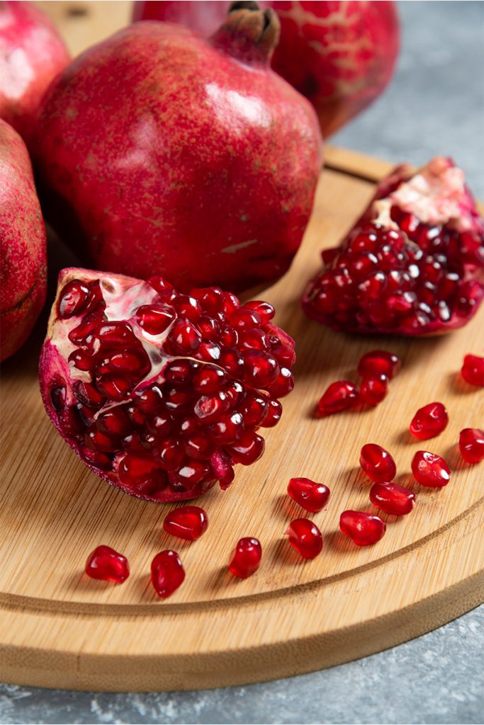 Sliced ripe pomegranate wooden board 683x1024